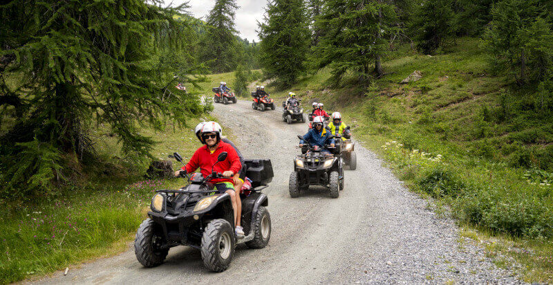 diversi quad guidati da conducenti con passeggeri sul sentiero in bosco