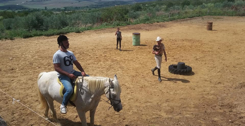 Insegnante equestre che guida un allievo in sella a cavallo
