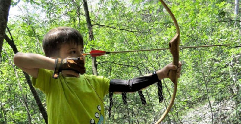 Bambino prova il tiro con l’arco con attrezzatura sicura